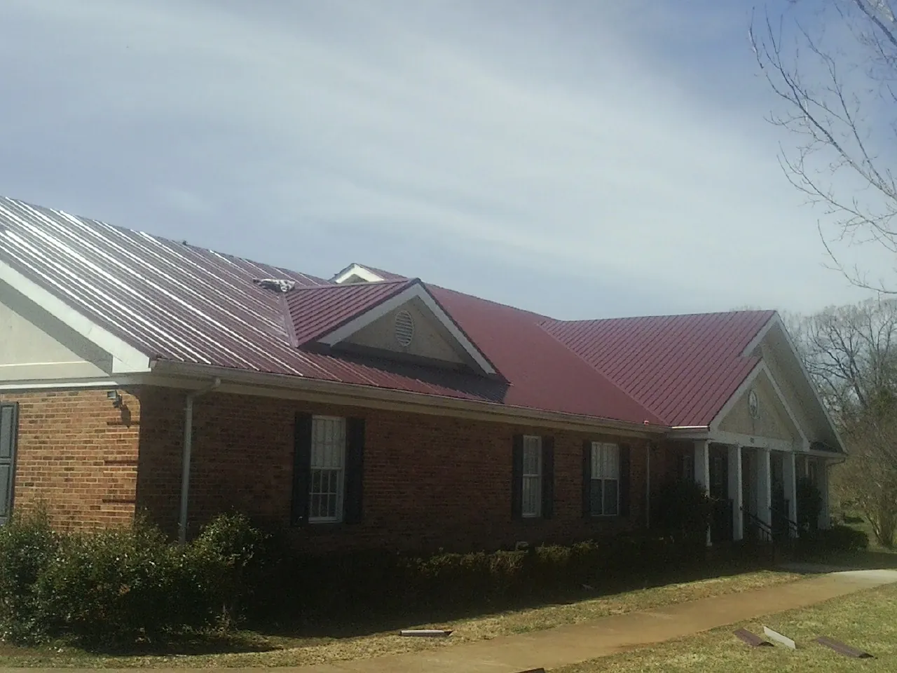 Red metal roof with gabled entries on a long brick building in Pembroke