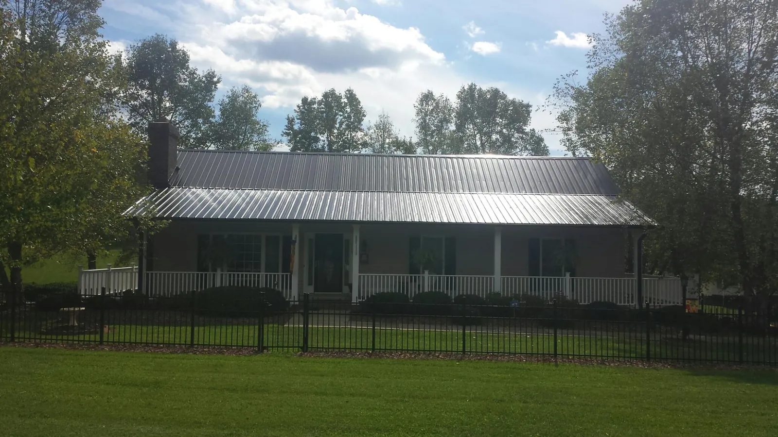 Gray metal roof on a brick ranch with a full width front porch — Gutter Guard Installation work by our crew in Pembroke